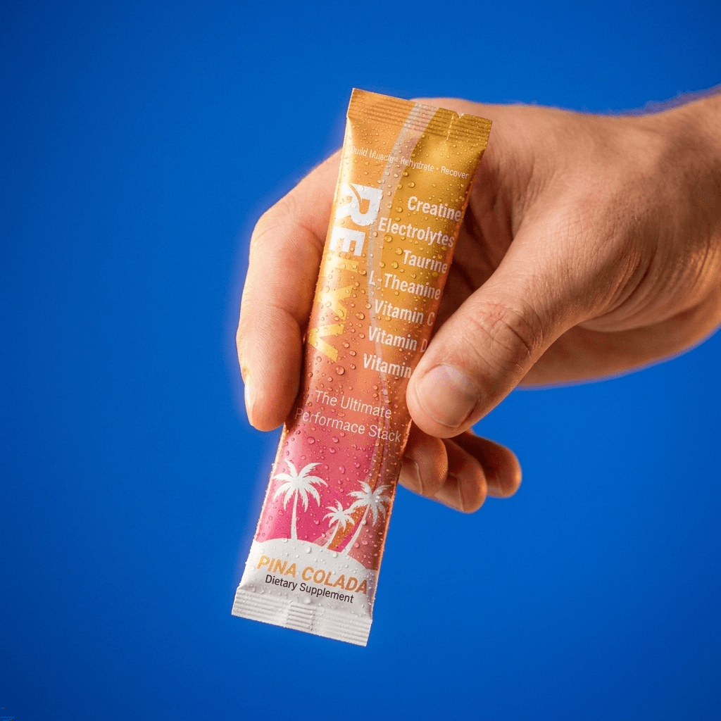 Hand holding a Relyv Performance Stack Piña Colada stick against a blue backdrop